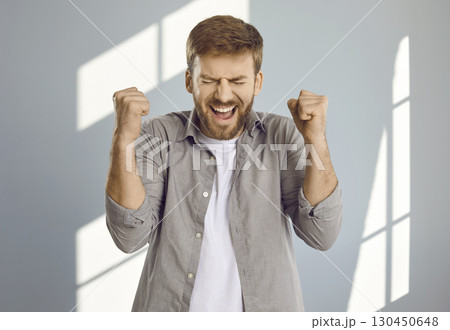 Portrait of young man celebrating success or clenching fists with anger and screaming 130450648