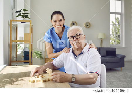 Elderly man with caregiver solving puzzles as memory training against Alzheimer's and dementia. Elderly man with caregiver solving puzzles as memory training against Alzheimer's and dementia. 130450666