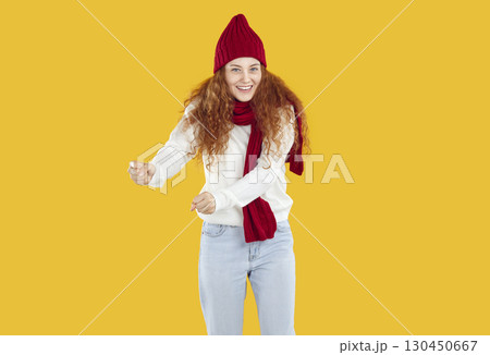 Funny woman in winter scarf and hat is having fun and dancing with satisfied expression on her face. 130450667