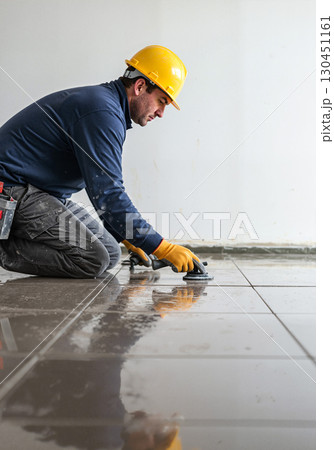 Focused worker installing tiles on a floor, craftsmanship and precision Focused worker installing tiles on a floor, craftsmanship and precision 130451161