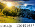 forest on the hill in rural area in mountains on autumn equinox. day and night time change concept. deciduous trees near grassy meadow in september with sun and moon at twilight 130451687