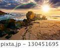 landscape by the sea at sunset in summer. beautiful beach with rocks washed by calm waves in evening light. view to horizon under rainbow and  blue sky with clouds. scenic travel destination for 130451695