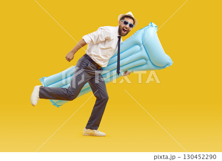 Happy, funny office worker holding beach mattress and running on yellow background 130452290