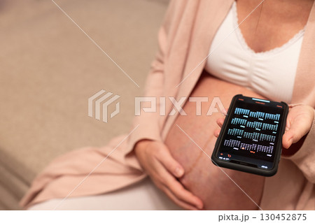 Pregnant woman looking at calendar in her phone. Baby birth date concept. Pregnant woman looking at calendar in her phone. Baby birth date concept. 130452875