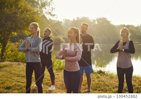 Yoga outdoors, happy young sport instructor in sportswear giving yoga master class to people Yoga outdoors, happy young sport instructor in sportswear giving yoga master class to people 130452882