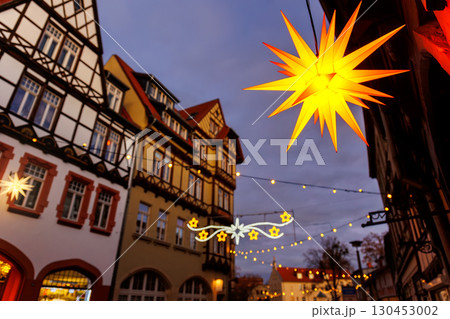 Charming Wernigerode town evening street view illuminated with Christmas lights garlands Herrnhutter stars on historical half-timbered houses facade. Twilight Festive city in Germany 130453002