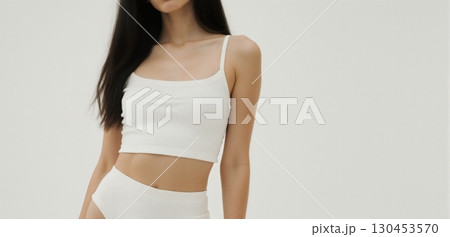 Young woman in white crop top posing indoors with minimal clean fashion style Young woman in white crop top posing indoors with minimal clean fashion style 130453570