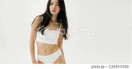 Young woman in white crop top posing indoors with minimal clean fashion style Young woman in white crop top posing indoors with minimal clean fashion style 130453580