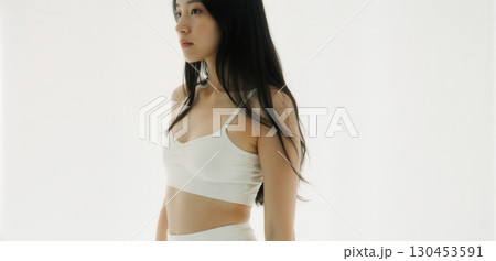 Young woman in white crop top posing indoors with minimal clean fashion style 130453591