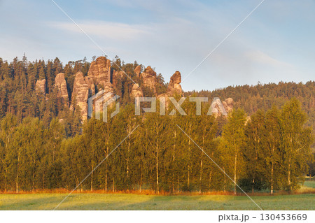 Adrspach-Teplice Rocks, sandstone formations in Hradec Kralove Region in the Czech Republic, Europe. A picturesque scene of sandstone formations rising above a forest, under a soft, muted sky at dawn. 130453669