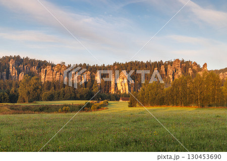 Adrspach-Teplice Rocks, sandstone formations in Hradec Kralove Region in Czech Republic, Europe. A scenic landscape featuring striking rock formations and lush green meadows, bathed in warm sunlight. Adrspach-Teplice Rocks, sandstone formations in Hradec Kralove Region in Czech Republic, Europe. A scenic landscape featuring striking rock formations and lush green meadows, bathed in warm sunlight. 130453690