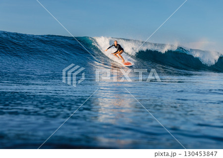 Surfer woman rides on surfboard on breaking wave, surfing in Bali. 130453847