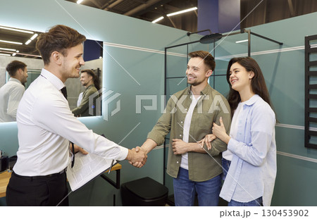 Plumbing Store Salesman Shaking Hands With Couple Plumbing Store Salesman Shaking Hands With Couple 130453902