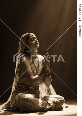 Young indian woman wearing traditional clothing and jewelry is sitting with her hands together in prayer 130454633