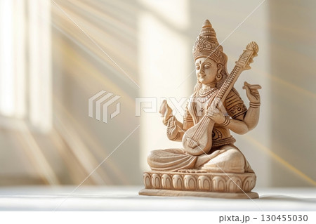 Wooden statue of goddess Saraswati playing a string instrument representing wisdom, art, and music in Hinduism 130455030