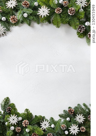 Christmas frame with evergreen branches and carving wooden eco natural decorations, snowflakes, pine cones on white background. Copy space. Xmas vertical greeting card. Winter Holiday. View from above Christmas frame with evergreen branches and carving wooden eco natural decorations, snowflakes, pine cones on white background. Copy space. Xmas vertical greeting card. Winter Holiday. View from above 130455949