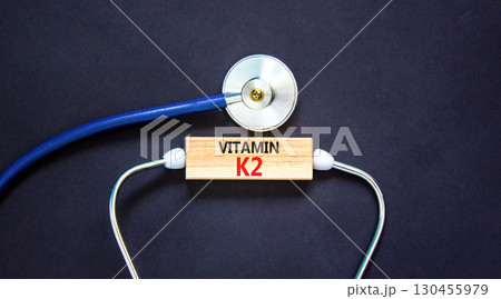 Vitamin K2 phylloquinone symbol. Concept words Vitamin K2 on beautiful wooden block. Stethoscope. Beautiful black background. Medical healthy lifestyle Vitamin K2 phylloquinone concept. 130455979