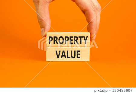 Property value symbol. Concept words Property value on beautiful wooden blocks. Beautiful orange table orange background. Businessman hand. Business property value concept. Copy space. Property value symbol. Concept words Property value on beautiful wooden blocks. Beautiful orange table orange background. Businessman hand. Business property value concept. Copy space. 130455997