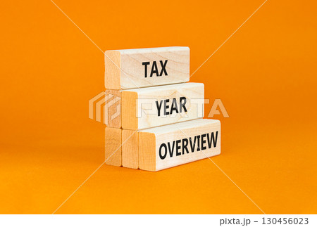 Tax year overview symbol. Concept words Tax year overview on beautiful wooden blocks. Beautiful orange table orange background. Business tax year overview concept. Copy space. 130456023
