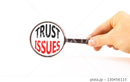 Trust issues symbol. Concept word Trust issues on beautiful magnifying glass. Businessman's hand. Beautiful white paper background. Black magnifying glass. Business trust issues concept. Copy space. 130456115