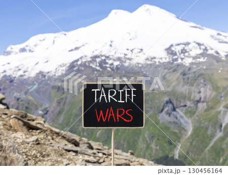 Trade tariff wars symbol. Concept word Tariff wars on beautiful black blackboard. Beautiful stone mountain Elbrus blue sky background. Black blackboard. Business trade tariff wars concept. Copy space. Trade tariff wars symbol. Concept word Tariff wars on beautiful black blackboard. Beautiful stone mountain Elbrus blue sky background. Black blackboard. Business trade tariff wars concept. Copy space. 130456164