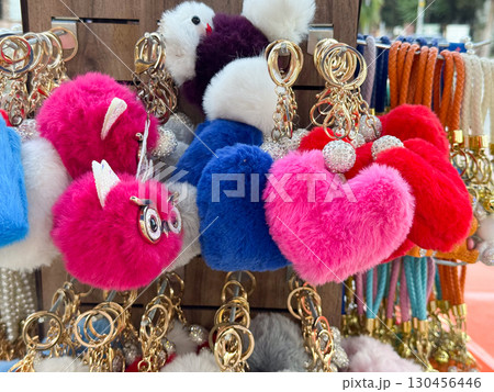 Plush heart keychains in bright colors displayed on a rack. Fashion accessory, retail decoration, textile charm and seasonal gift concept. 130456446