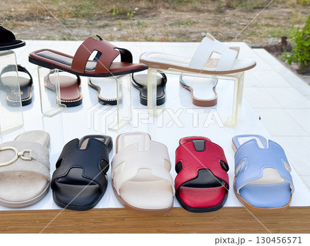 Summer sandals in different colors arranged on display table. Footwear, fashion, and lifestyle shopping concept in consumer retail commerce. 130456571