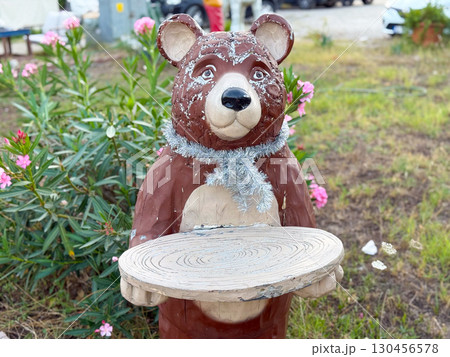 Decorative bear statue holding wooden tray in outdoor environment. Art, culture, and amusement concept in urban lifestyle installation. Decorative bear statue holding wooden tray in outdoor environment. Art, culture, and amusement concept in urban lifestyle installation. 130456578