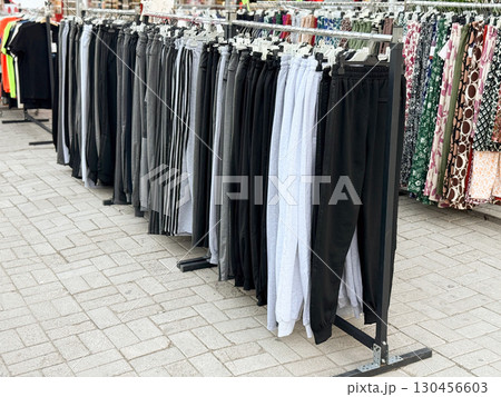 Collection of pants and trousers displayed on hangers in street market. Apparel, shopping, and consumer lifestyle concept in retail environment. 130456603