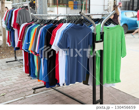 Rack of colorful t-shirts displayed in open street market. Consumer shopping, casual apparel, and lifestyle fashion in retail environment. Rack of colorful t-shirts displayed in open street market. Consumer shopping, casual apparel, and lifestyle fashion in retail environment. 130456659