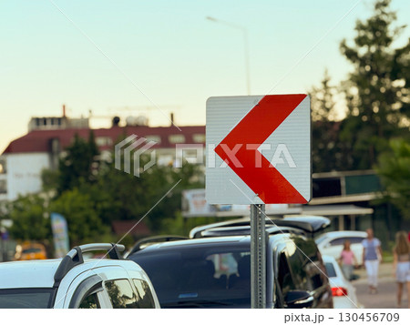 Red arrow traffic sign on a post. Road safety, direction and urban navigation. 130456709