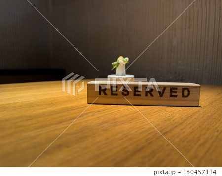Reserved sign on wooden table with soft lighting, modern minimalistic decor in restaurant. Focused on sign and clean, natural elements creating an elegant dining atmosphere 130457114