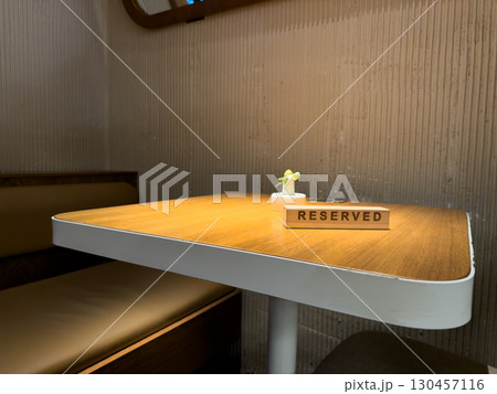 Reserved sign on restaurant table in cozy booth, emphasizing importance of early reservation in busy, popular cafe. Ideal for customers looking for guaranteed seating in high demand locations 130457116