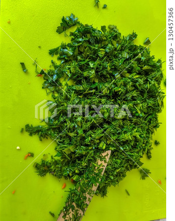 Chopped green parsley herbs on cutting board ready for cooking use and garnish Chopped green parsley herbs on cutting board ready for cooking use and garnish 130457366