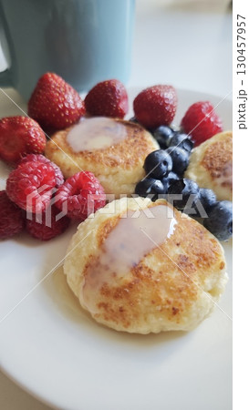 Cheese pancakes with condensed milk served with fresh strawberries, raspberries and blueberries 130457957