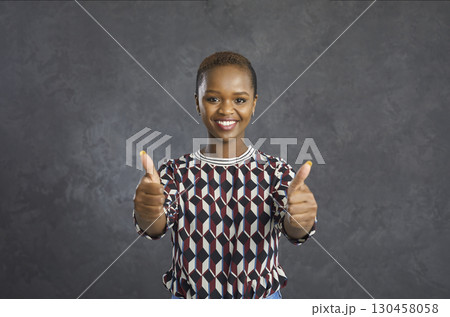 Portrait of a happy satisfied young African woman giving a thumbs up and smiling Portrait of a happy satisfied young African woman giving a thumbs up and smiling 130458058