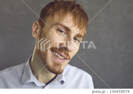 Closeup studio portrait of happy confident redhead man looking at camera and smirking Closeup studio portrait of happy confident redhead man looking at camera and smirking 130458074