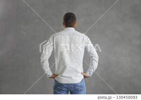 Back view of man in denim shirt standing hands on hips isolated on grey background 130458093