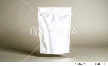 Close-up of a plain white resealable plastic pouch standing upright on a neutral surface with a subtle background, suitable for packaging or storage purposes Close-up of a plain white resealable plastic pouch standing upright on a neutral surface with a subtle background, suitable for packaging or storage purposes 130458134