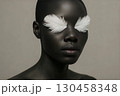 Dark-Skinned Model with Decorative White Feathers on Eyes 130458348
