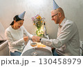 Couple Birthday Celebration Dinner Party: Indoors, intimate birthday celebration for a couple, wearing party hats, sharing a meal and drinks. 130458979