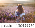 Lavender Woman Flowers: Smiling girl holds flowers in lavender field during sunny day, enjoying the fragrance. 130459559