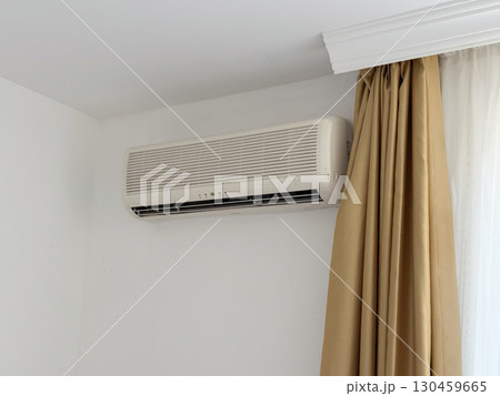 Air conditioning unit on wall of hotel room providing cooling and comfort. Climate control, efficiency and essential element of seasonal travel accommodation and indoor lifestyle. 130459665