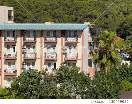Facade of multi-storey hotel building with balconies and air conditioning units. Architecture, urban housing, accommodation, hospitality and exterior structural design. 130459683