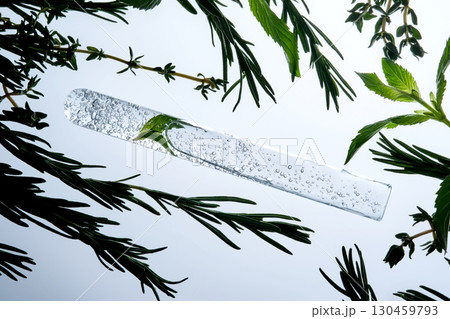 A test tube with the texture of serum or other cosmetics with mint and herbs. A test tube with the texture of serum or other cosmetics with mint and herbs. 130459793