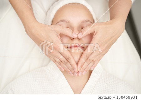 Young caucasian female receiving facial massage in spa with relaxing heart-shape 130459931