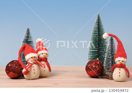 Christmas background with knitted snowmen in red hats and Christmas trees with red ball and space for text, greetings, promotions, and discounts. Christmas and New Year card. 130459972