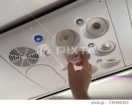 Male hand adjusting air vent in airplane cabin. Passenger comfort, aviation technology, and travel experience. 130460363