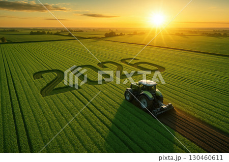 Aerial view of green farmland with tractor creating number "2026" in field under bright sunrise, symbolizing agricultural innovation and future growth 130460611