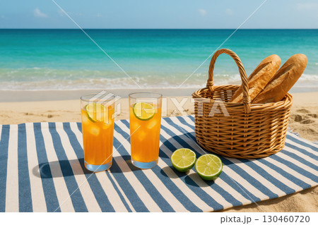 Beachside picnic with striped blanket, fresh bread wicker basket, iced orange drinks with lime halves, tropical vacation setup 130460720